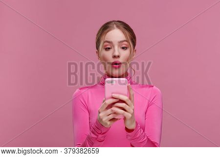 The Best Day Ever. Surpised Young Redhead Woman Holding Pink Smartphone, Smiling And Expressing Posi