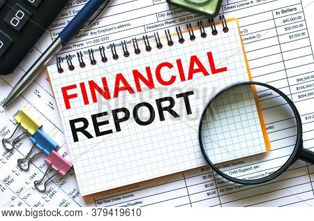 Text Financial Report On Notepad With Calculator, Clips, Pen On Financial Report