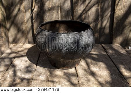 Vintage Cast-iron Pot Of Black Color On Wooden Boards On A Sunny Day Outdoor. Cooking Food.