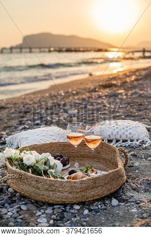 Vertical Image Of The Beach Picnic With Wine, Figs, Croissants And Camamber Cheese In A Woven Basket
