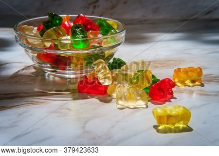 Assorted Flavors Of Gummy Bear Candies In Glass Dish On Marble Kitchen Table