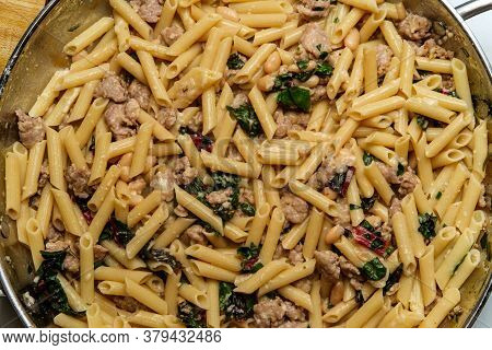 Italian White Wine Alfredo With Penna Pasta Sausage Cannellini And Red Chard Greens Cooking In Large