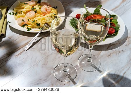Romantic Italian Dinner With Two Glasses Of Pinot Grigio White Wine And Fettuccine Alfredo Shrimp In