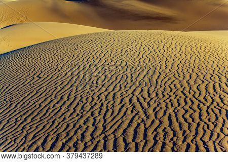 USA. The gentle slopes of the sand dunes are rippled by the wind. Mesquite Flat Sand Dunes is a picturesque part of Death Valley in California. Concept of active, ecological and photo tourism