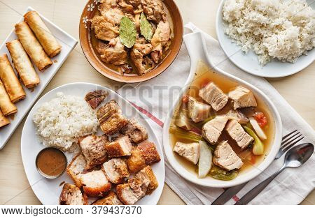 filipino dinner with sinigang, lechon kawali, and chicken adobo top down composition