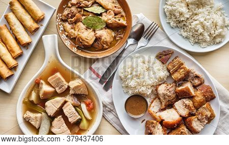 filipino dinner with sinigang, lechon kawali, and chicken adobo top down composition