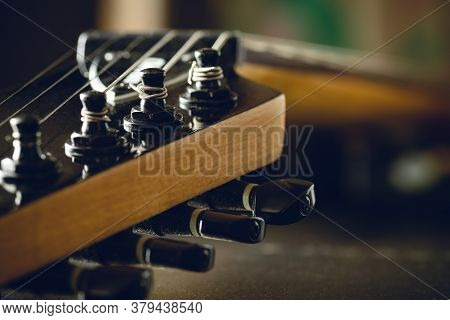Closeup Tuning Key On The Headstock Of The Black Electric Guitar In Dark Background And Morning Ligh