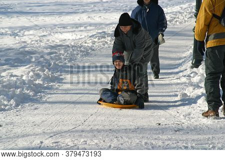 ZAGREB, CROATIA - JANUARY 12, 2014: Landscape view of a snowy hill with families with children and people sledging and having fun in snow, Park Maksimir in Zagreb, Croatia