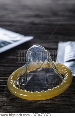 World Sexual Helth Day. The Unpacked Condom Lies Next To The Packed Cones On An Old Wooden Backgroun