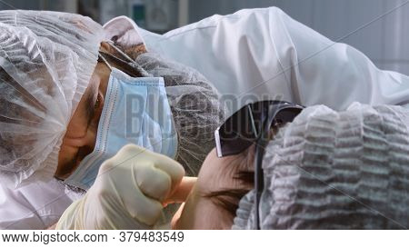 Suturing stitches. Oral surgeon performing surgery installing implant into senior woman mouth. Dentist works with a patient in modern dental clinic