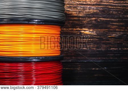 Three Coils Of Filament For 3d Printing. Bright Thermoplastic Of Orange, Red And Grey Colors.