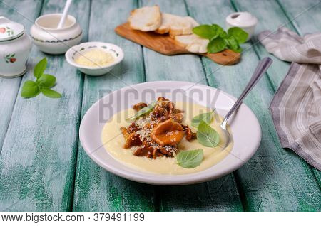 Traditional Polenta With Mushrooms And Cheese In A Dish On A Green Wooden Background. Selective Focu