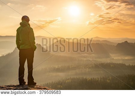Woman Stands Alone On The Peak Of Rock. Hiker Watching To Autumn Sun At Horizon . Beautiful Moment T