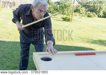 Man Playing Novuss In Outdoors. Novuss Is A National Sport In Latvia Similar To Pocket Billiards Or 