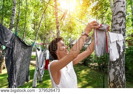 Candid Real Life Portrait Of Young Adult Beautiful Attractive Caucasian Woman Hanging Up Fresh Washe