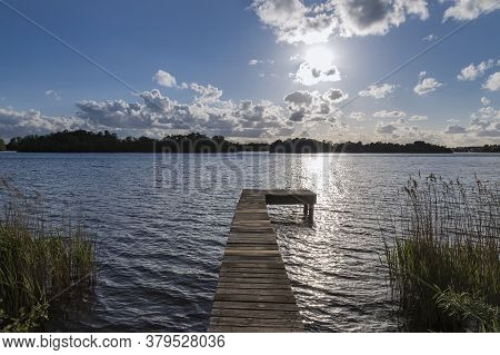 Water Canal At Glimmen Site In Holland. The Background Is A Blue Sky With White Clouds. A Wooden Pie