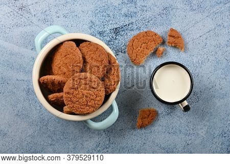 Close Up Round Artisan Oatmeal Cookies And Pannikin Mug Of Milk On Blue Painted Rustic Wooden Table,