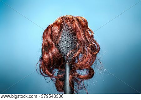 Females Hair. Black Hairbrush With A Red Wig, Looks Like A Womans Head With A Hairstyle. Blue Backgr