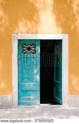 Open Green Double-barrelled Doors With Bars Against The Yellow Wall