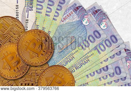 1000 Indonesian Rupiah Bills And Golden Bitcoins. Cryptocurrency Investment Concept. Crypto Mining O