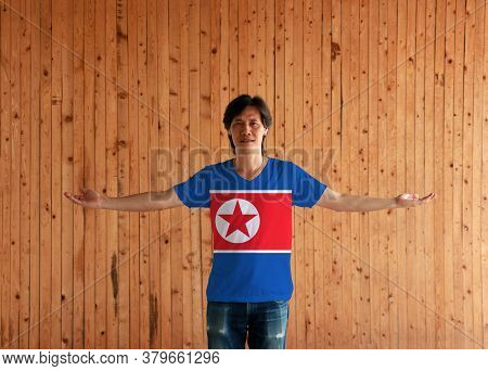 Man Wearing North Korea Flag Color Shirt And Standing With Arms Wide Open On The Wooden Wall Backgro