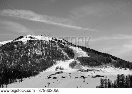 Snowy Ski Slope With Ski-lifts, Traces And Forest In High Winter Mountains At Sunny Morning. Italian
