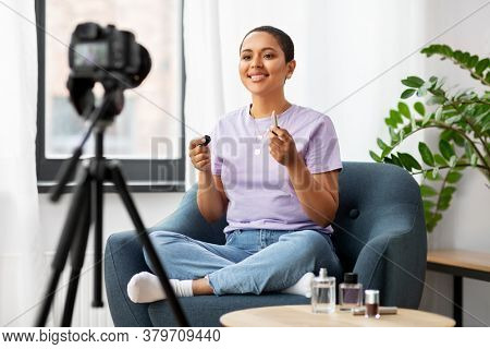 blogging, videoblog and people concept - happy smiling african american female beauty blogger with camera and make up cosmetics videoblogging at home