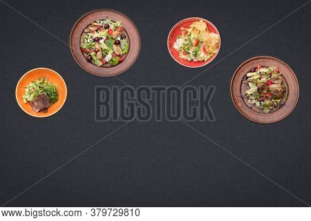 Four Salads On A Black Background Lie In A Semicircle With Sopy Space