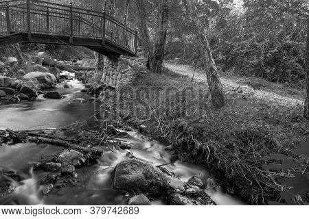 Bridge Over Smooth Flowing Water Stream At The Vateri Footpah In Kakopetria, Troodos, Cyprus