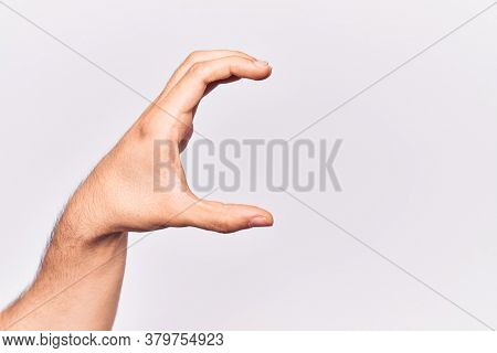 Close up of hand of young caucasian man over isolated background picking and taking invisible thing, holding object with fingers showing space 