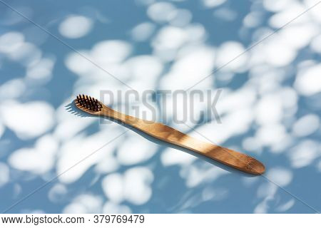 Bamboo Toothbrush On Light Blue Pastel Background With Shadows Of Natural Light. Biodegradable Peson