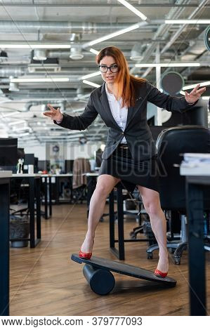 A Woman In A Suit Is Engaged On A Rocker-skateboard During A Break At Work. A Female Office Employee
