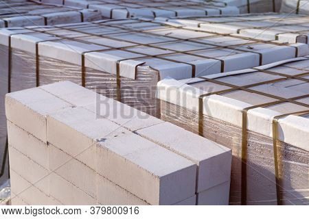 Silicate Brick On Wooden Pallets Wrapped In Transparent Plastic Wrap At A Construction Site
