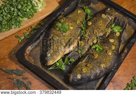 The Tench Fish Is Baked In The Oven And Seasoned With Spices, Fried Onions And Fresh Green Parsley L
