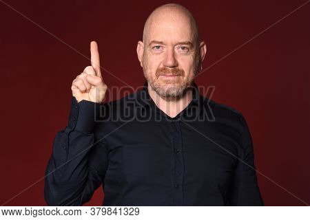 Portrait Of A Man With Fingers Making Number One On Red Background