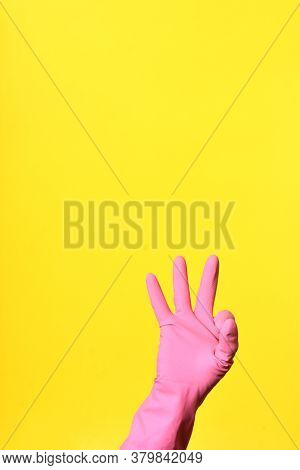 Hand With Glove And Sign Ok On Yellow Background