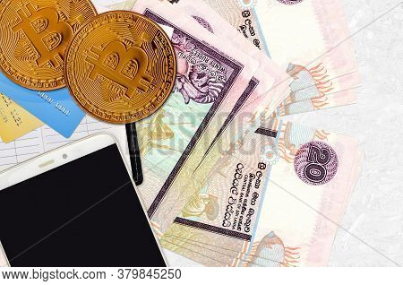 20 Sri Lankan Rupees Bills And Golden Bitcoins With Smartphone And Credit Cards. Cryptocurrency Inve