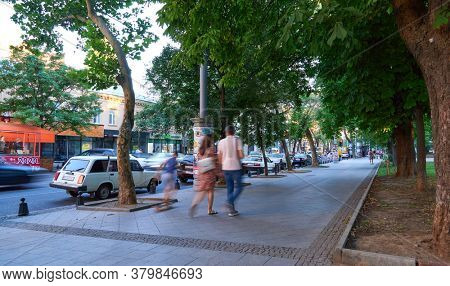 Odessa, Ukraine - August 4, 2020: Preobrazhenskaya street near the Cathedral square and city Park, green trees and people, road with car traffic