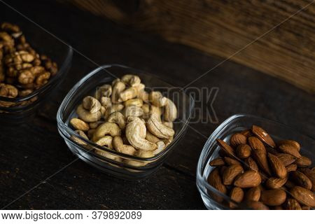 Almond, Cachew And Walnut In A Small Plates Which Standing On A Black Table. Nuts Is A Healthy Veget