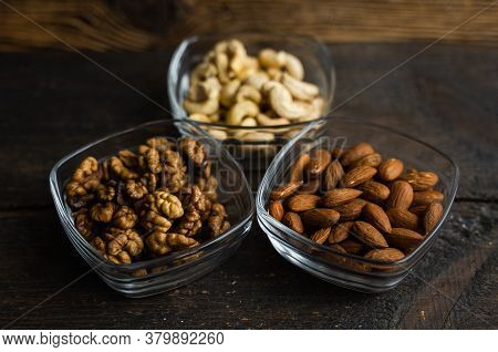 Almond, Cachew And Walnut In A Small Plates Which Standing On A Black Table. Nuts Is A Healthy Veget