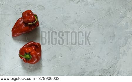 Two Ugly Fresh Red Peppers On A Gray Stone Background. Horizontally, With Space, Top View
