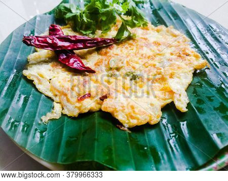 Omelette With Coriander Leaves And Red Chillies In A Banana Leaf.the Banana Leaf Has Green Color And