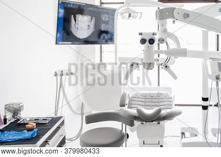 Interior Of Dental Practice Room With Chair, Lamp, Dental Scan On The Display And Stomatological Too