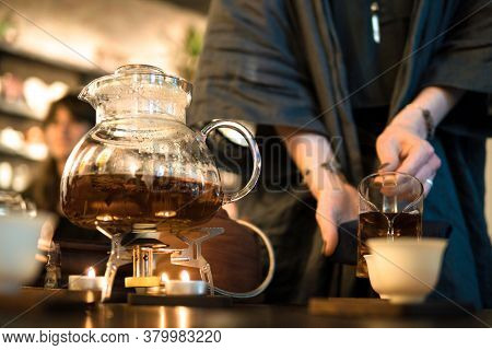 Traditional Chinese Tea Ceremony. Black Or Red Tea Pouring From A Glass Seethrough Chahai Into White