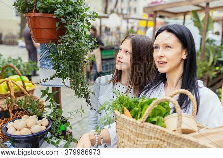 Two Sisiters Buying From An Organic Vegetable Stall At A Farmers Market, On A Sunny Morning, Young W