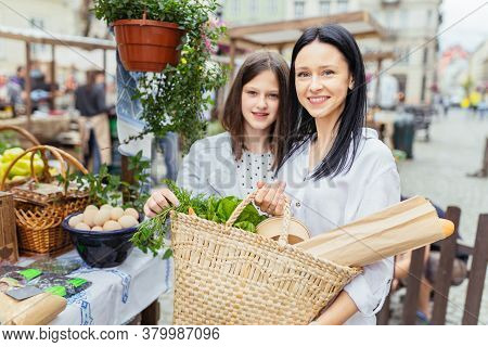 Two Sisiters Buying From An Organic Vegetable Stall At A Farmers Market, On A Sunny Morning, Young W