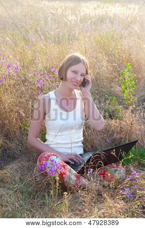 Donna positiva con Notebook e cellulare sul prato