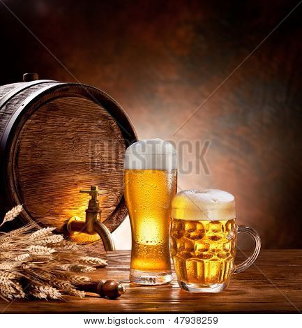 Barile di birra con bicchieri di birra su un tavolo di legno. Lo sfondo scuro.