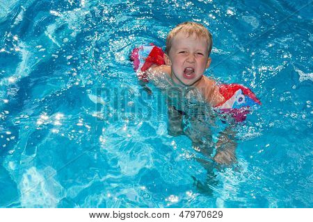 เด็กชาย Swims ในสระว่ายน้ำ