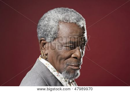 Widok z boku zbliżenie starszy człowiek African American z kolczyki na czerwonym tle